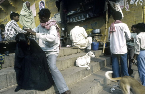 Homme se faisant couper les cheveux, près d'un ghât, Varanasi, Inde.